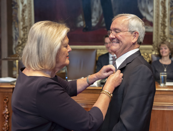 Hamilton ontvangt uit handen van de Voorzitter het lintje horende bij de versierselen van Officier in de Orde van Oranje-Nassau