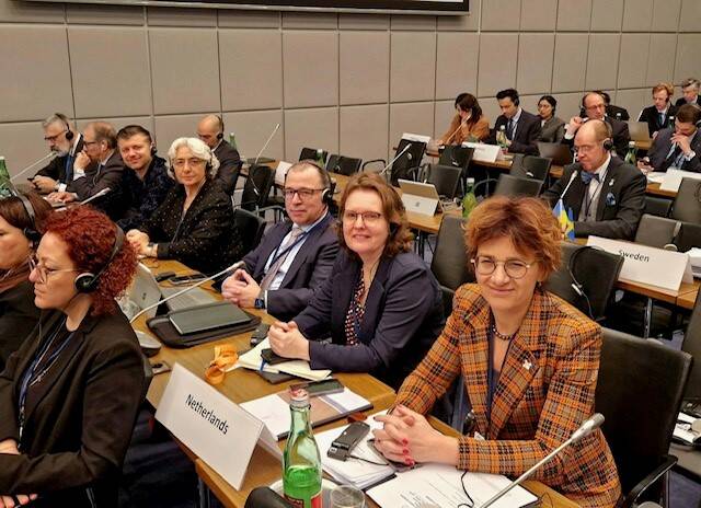 Foto van een vergaderzaal met de op de voorgrand leden van de Nederlandse delegatie
