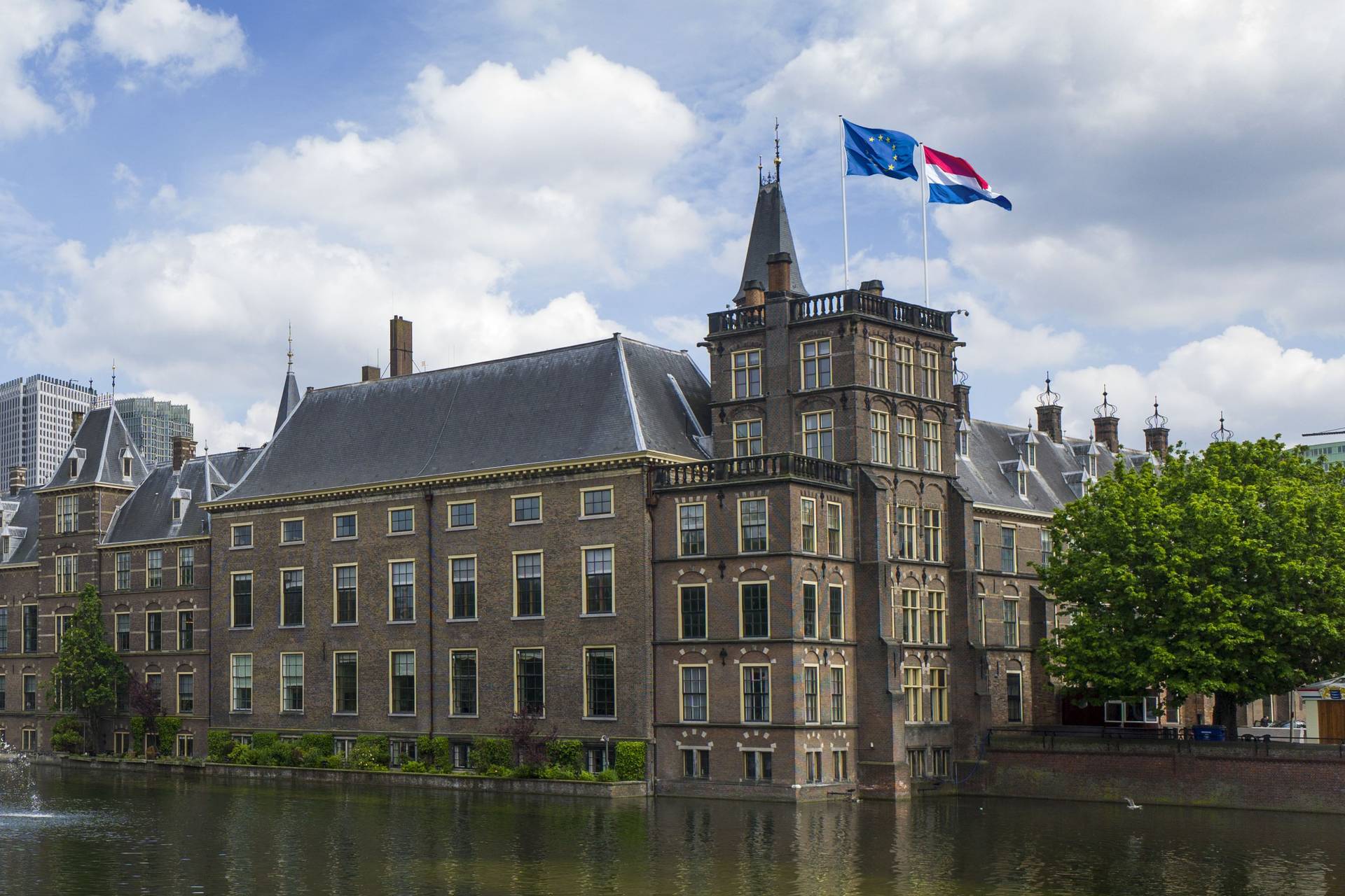De gebouwen van de Eerste Kamer aan de Hofvijver met de hoektoren en de Mauritstoren, waarop de Nederlandse en de Europese vlag wapperen.